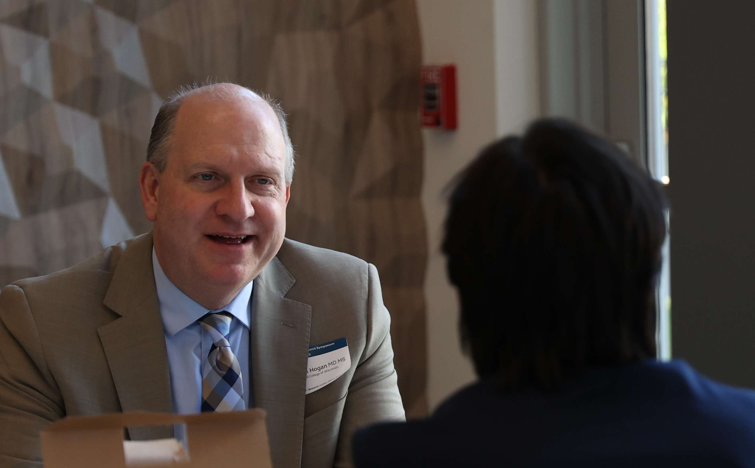 William Hogan, MD, MS speaking with a colleague.